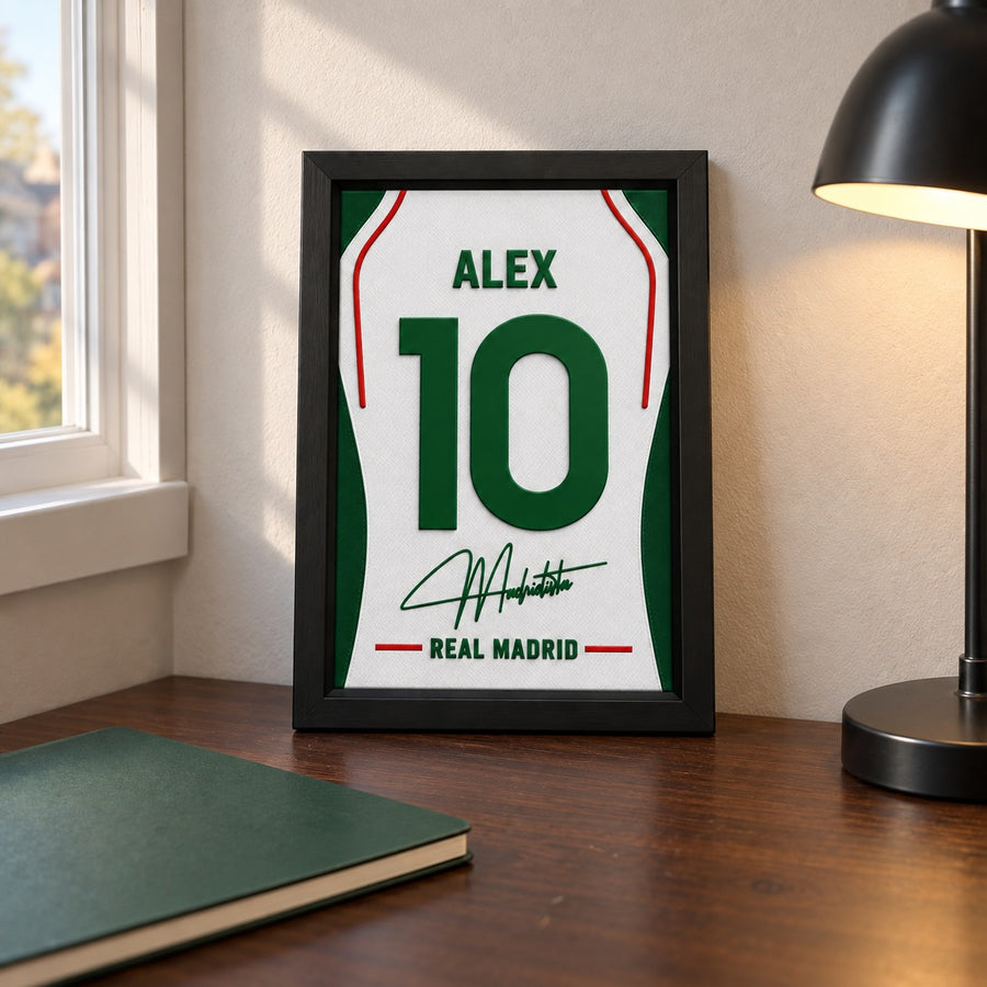 Real Madrid jersey frame personalized with ALEX and the number 10, standing on a desk beside a black lamp and a green notebook.
