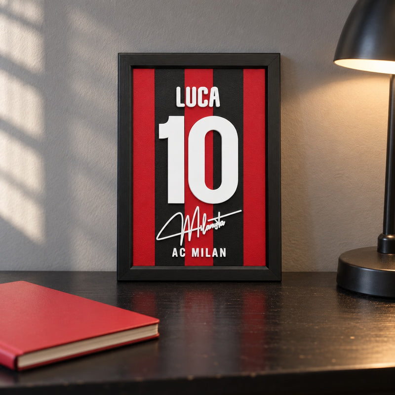AC Milan jersey frame personalized with LUCA and the number 10, standing on a desk beside a black lamp and a red notebook.