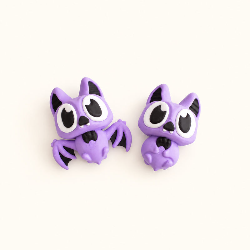Two purple articulated bats with large black and white eyes on a soft white background.