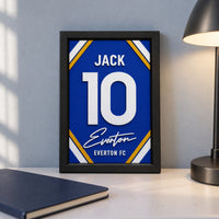 Everton jersey frame personalized with JACK and the number 10, standing on a desk beside a black lamp and a navy notebook.