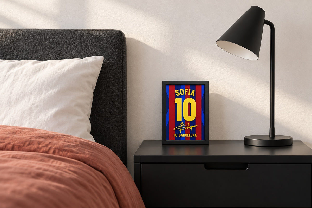 Barcelona jersey frame personalized with SOFIA on a bedside table beside a black lamp and a terracotta duvet.