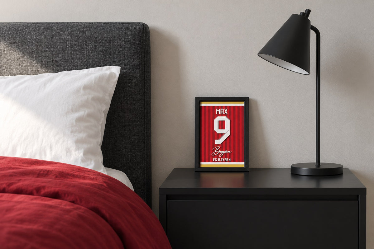 Bayern Munich jersey frame personalized with MAX on a bedside table beside a black lamp and a red duvet.