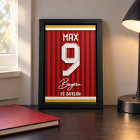 Bayern Munich jersey frame personalized with MAX and the number 9, standing on a desk beside a black lamp and a red notebook.