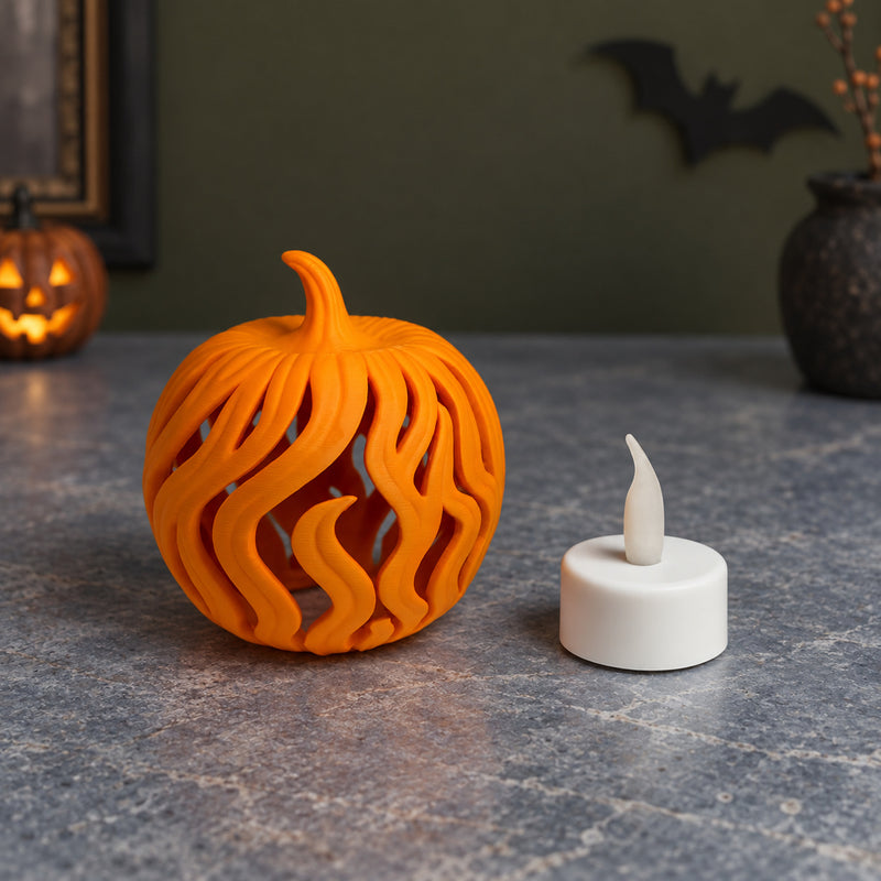 Orange pumpkin with long flame-shaped openings beside a white LED tealight in a styled home setting.