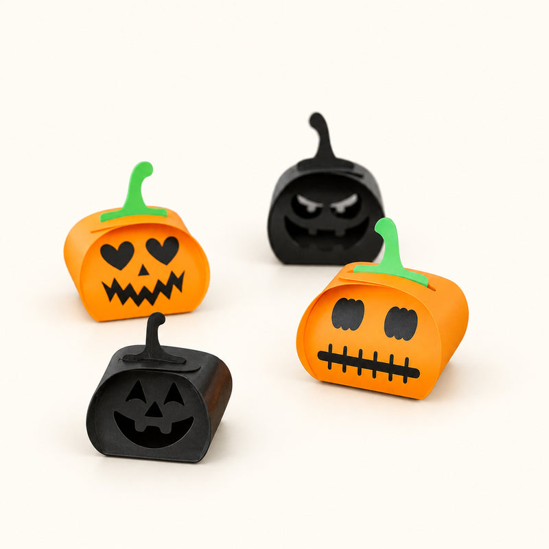 Orange and black folding pumpkin designs with different faces and green stems on a soft white background.