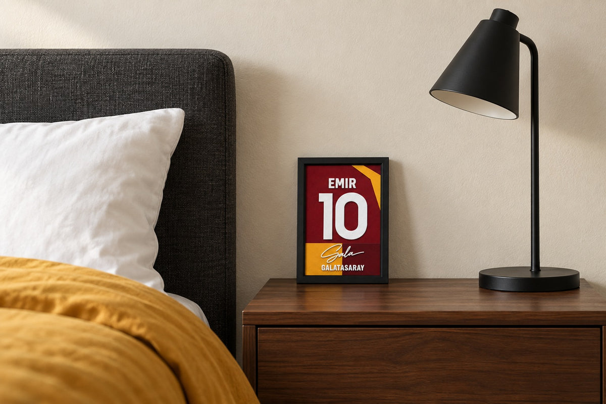 Galatasaray jersey frame personalized with EMIR on a bedside table beside a black lamp and a mustard duvet.
