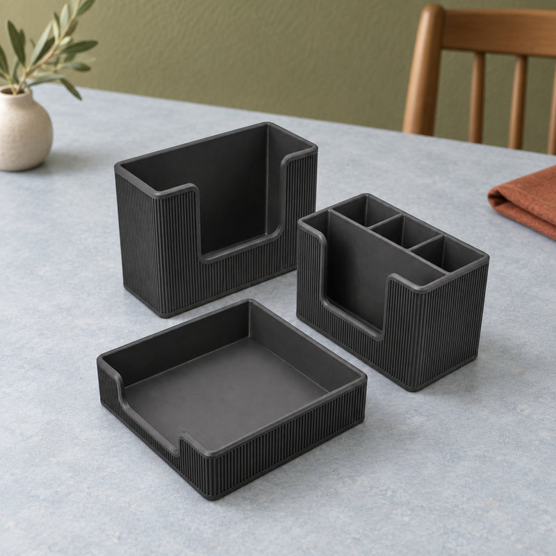 Three black rectangular dining organizers including a shallow tray and upright holders in a styled home setting.