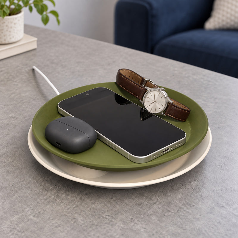 Olive and cream round tray lamp holding a phone, brown-strapped watch and charcoal earbud case in a styled home setting.