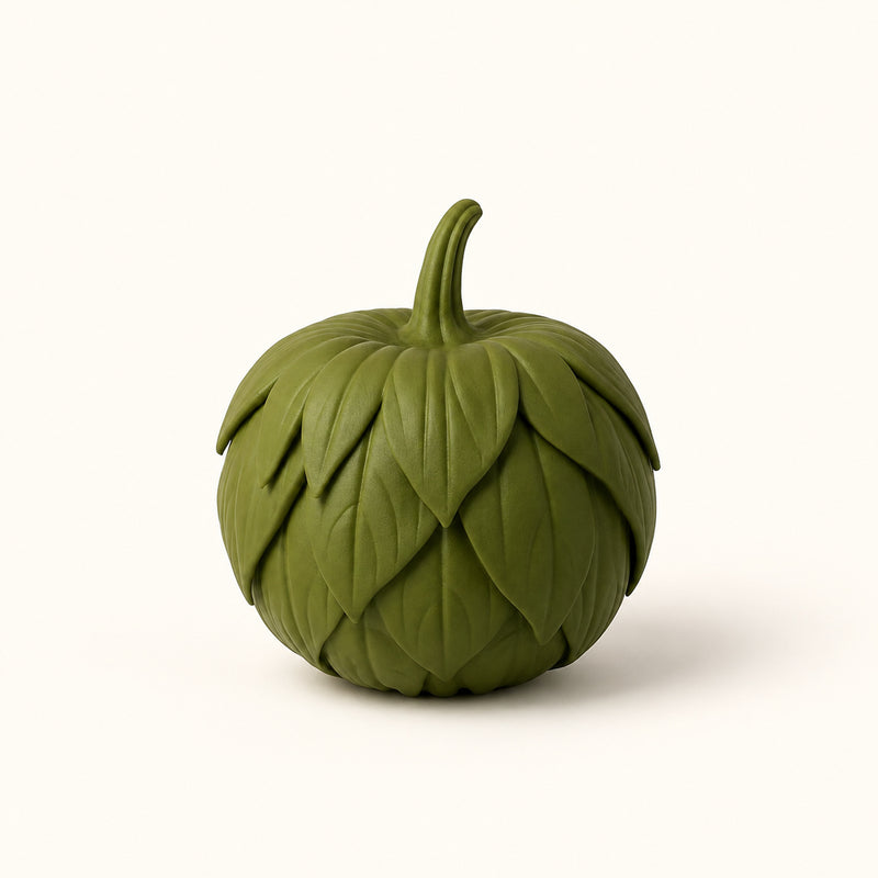 Green pumpkin decoration covered in overlapping sculpted leaves on a soft white background.