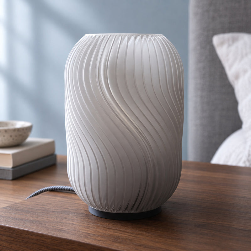 Pale upright table lamp with twisting vertical flutes and a visible cable in a styled home setting.