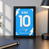 Manchester City jersey frame personalized with OLIVER and the number 10, standing on desk.
