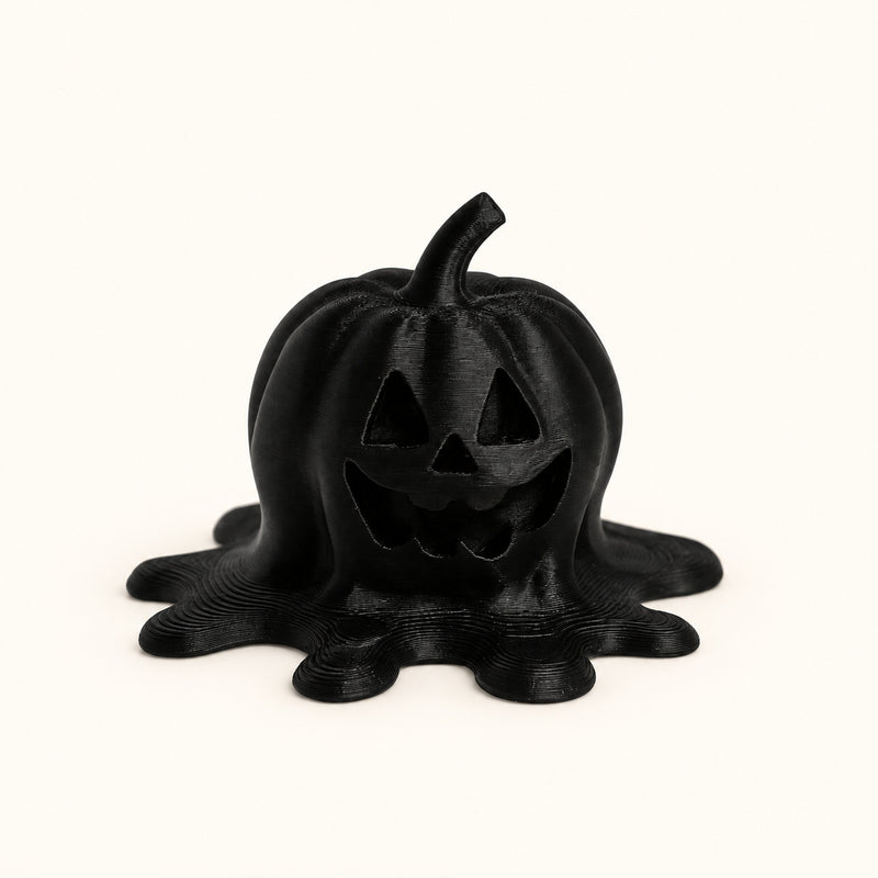 Black jack-o’-lantern decoration with a spreading melting base on a soft white background.