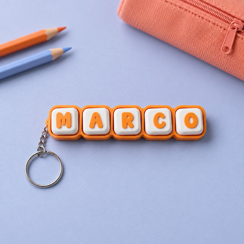 Orange and white MARCO name clicker with a silver keyring in a styled home setting.