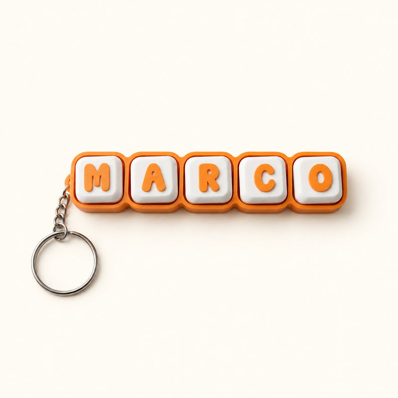 Orange and white MARCO name clicker with a silver keyring on a soft white background.