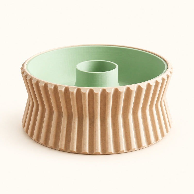 Empty pistachio bowl with tan fluted outer walls, a green interior and a raised open centre on a soft white background.