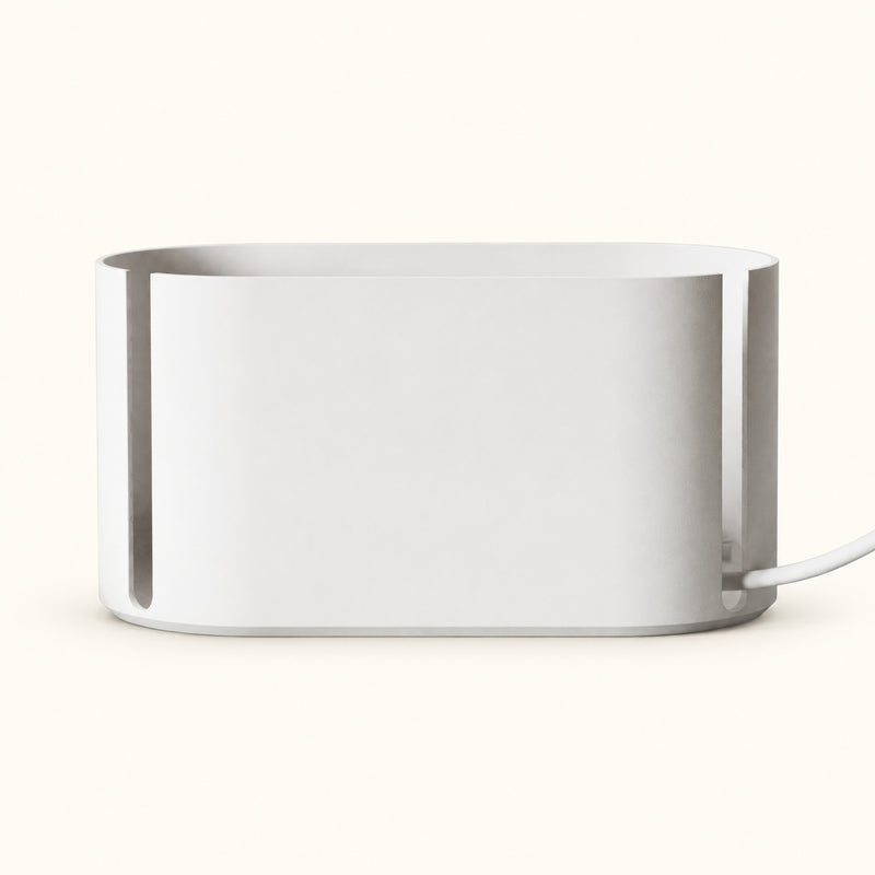 White rounded cable management box with narrow side slots and a cable on a soft white background.