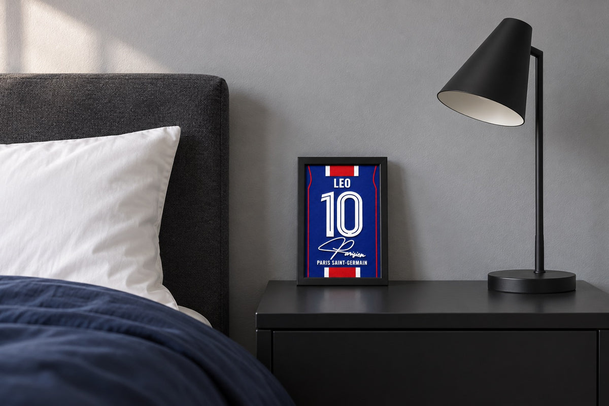 Paris Saint-Germain jersey frame personalized with LEO on a bedside table beside a black lamp and a navy duvet.