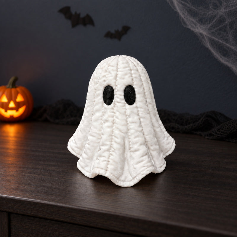 White quilt-textured ghost with black oval eyes in a styled home setting.