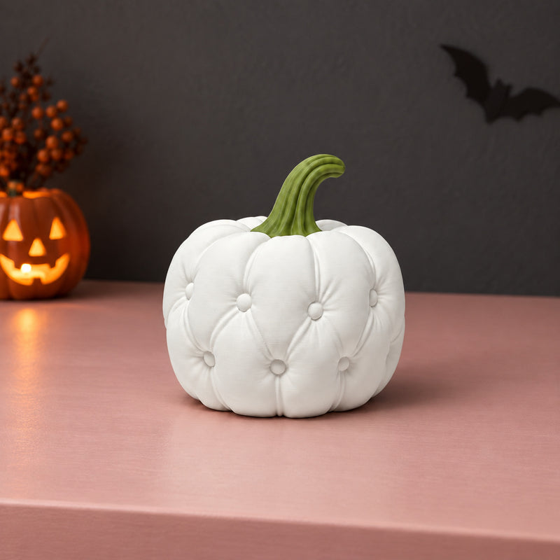 White quilt-style pumpkin decoration with a green stem in a styled home setting.