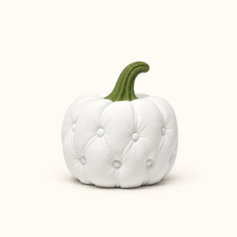 White quilt-style pumpkin decoration with a green stem on a soft white background.