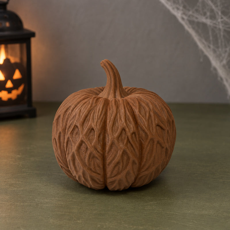 Brown pumpkin decoration covered in intertwined root-like detailing in a styled home setting.