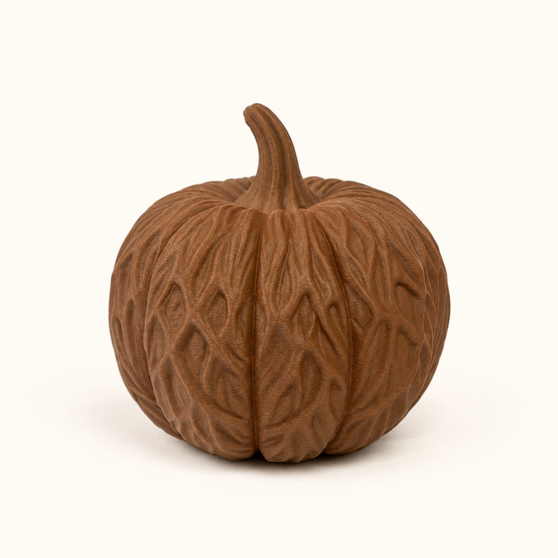 Brown pumpkin decoration covered in intertwined root-like detailing on a soft white background.
