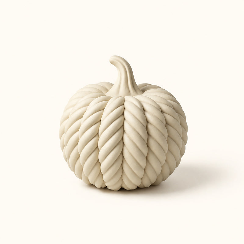 Cream pumpkin decoration with twisted rope-style ridges and a curved stem on a soft white background.