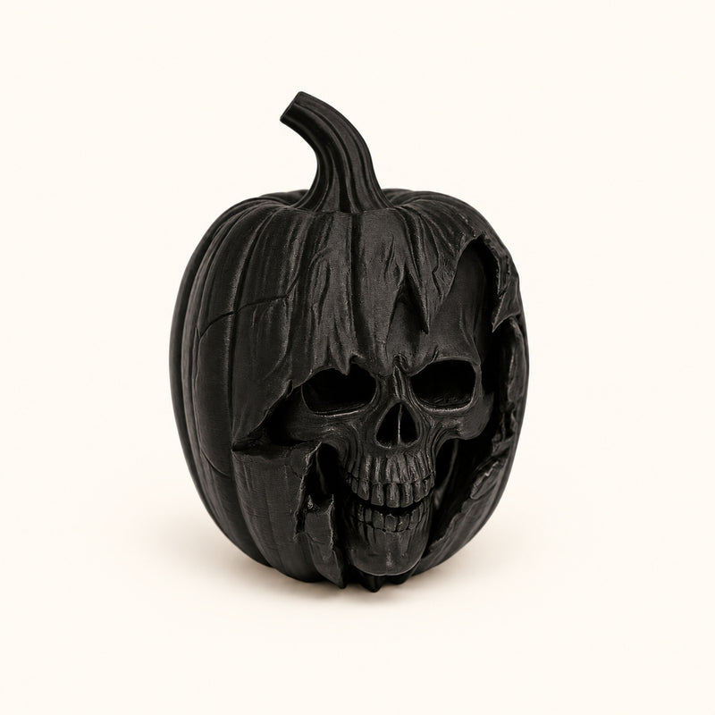 Black pumpkin decoration with a skull face sculpted into the front on a soft white background.