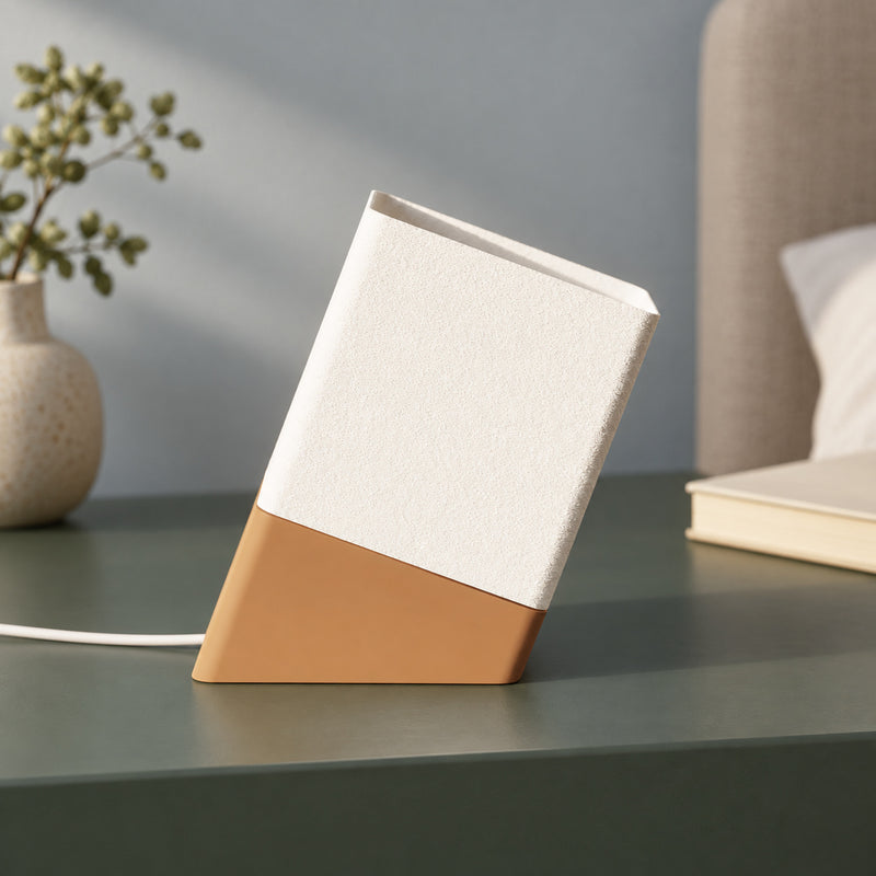 Slanted table lamp with a pale upper section and tan base in a styled home setting.