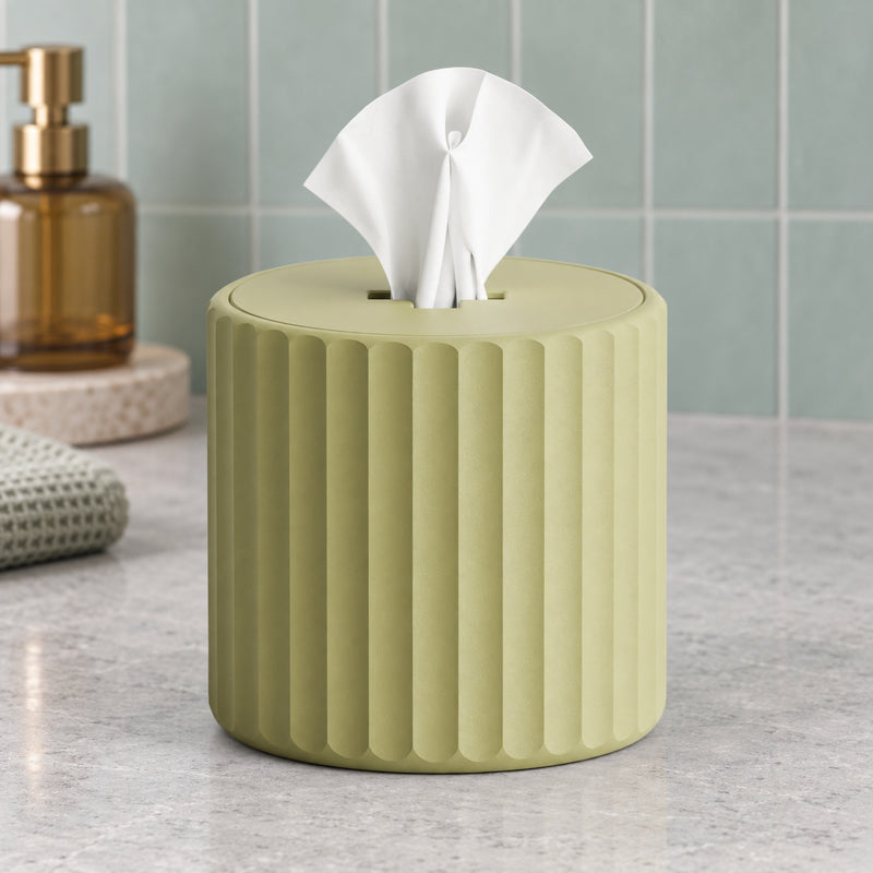 Green cylindrical fluted tissue holder with a white tissue emerging from the top in a styled home setting.