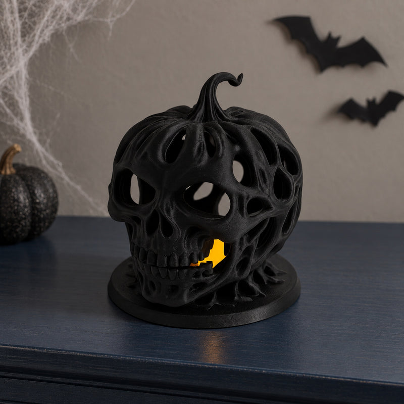Black openwork skull pumpkin lantern with irregular holes and a warm glow in a styled home setting.