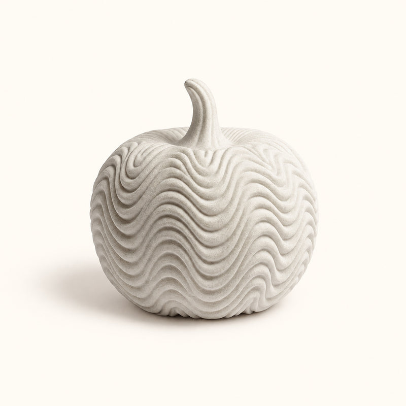 Pale pumpkin decoration with flowing wave-pattern ridges on a soft white background.